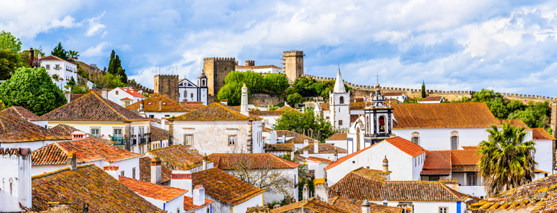 Obidos, Portugal:  Old town skyline with house roof tops, church towers, defence wall, medieval castle in the civil parish of Santa Maria, São Pedro e Sobral da Lagoa, Oeste region; Obidos village